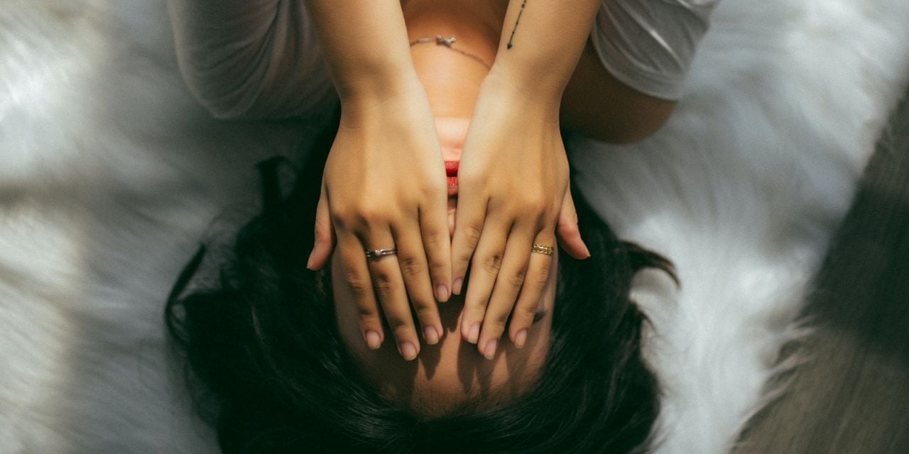 Une femme allongée avec les mains sur le visage