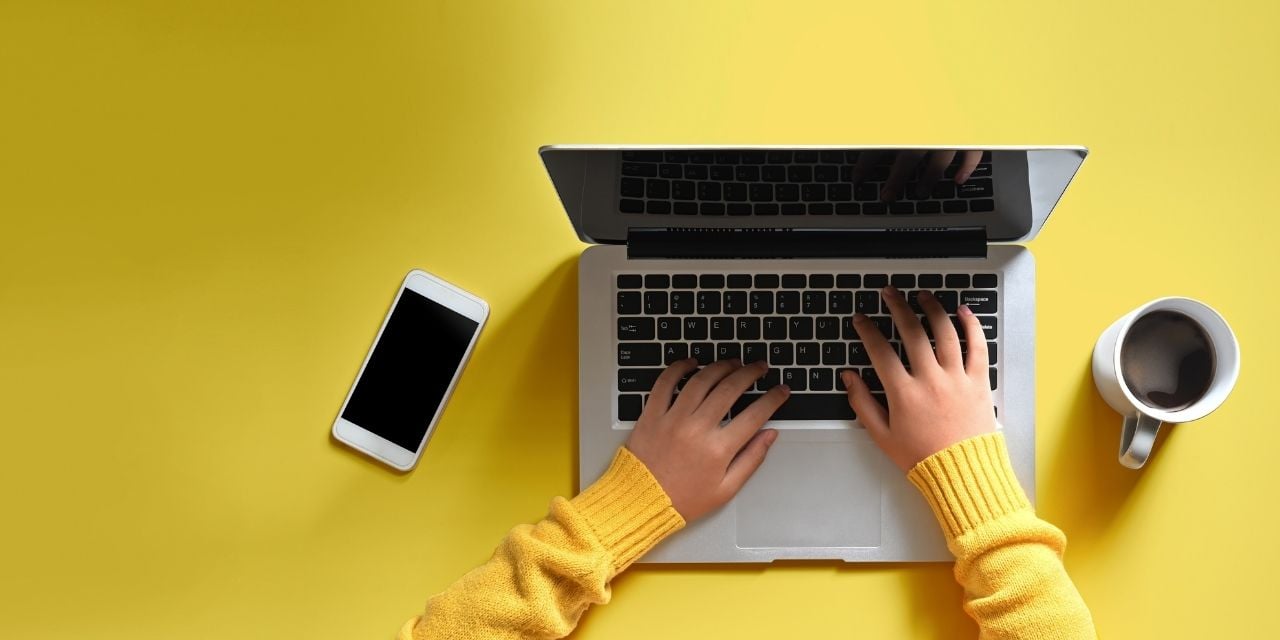 Une personne travaille sur un macbook sur fond jaune